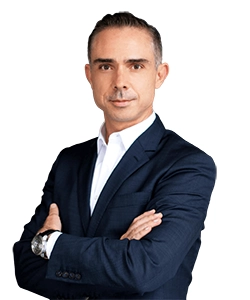 Professional headshot of a man in a navy suit with a white shirt, arms crossed, looking at the camera.