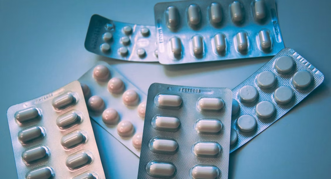 Multiple blister packs of white pills scattered on a blue surface.